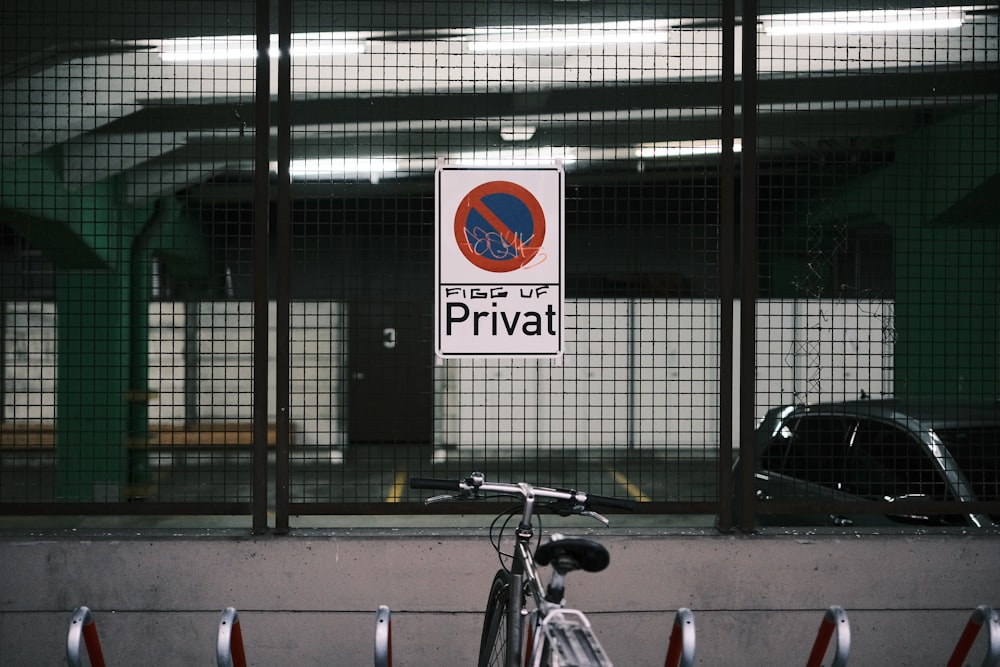 a bike parked next to a fence with a sign on it