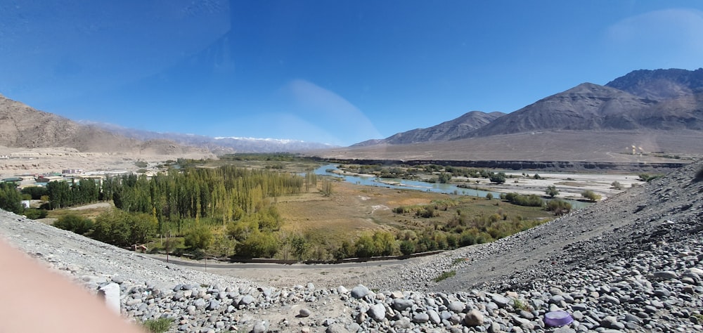 a person taking a picture of a river and mountains