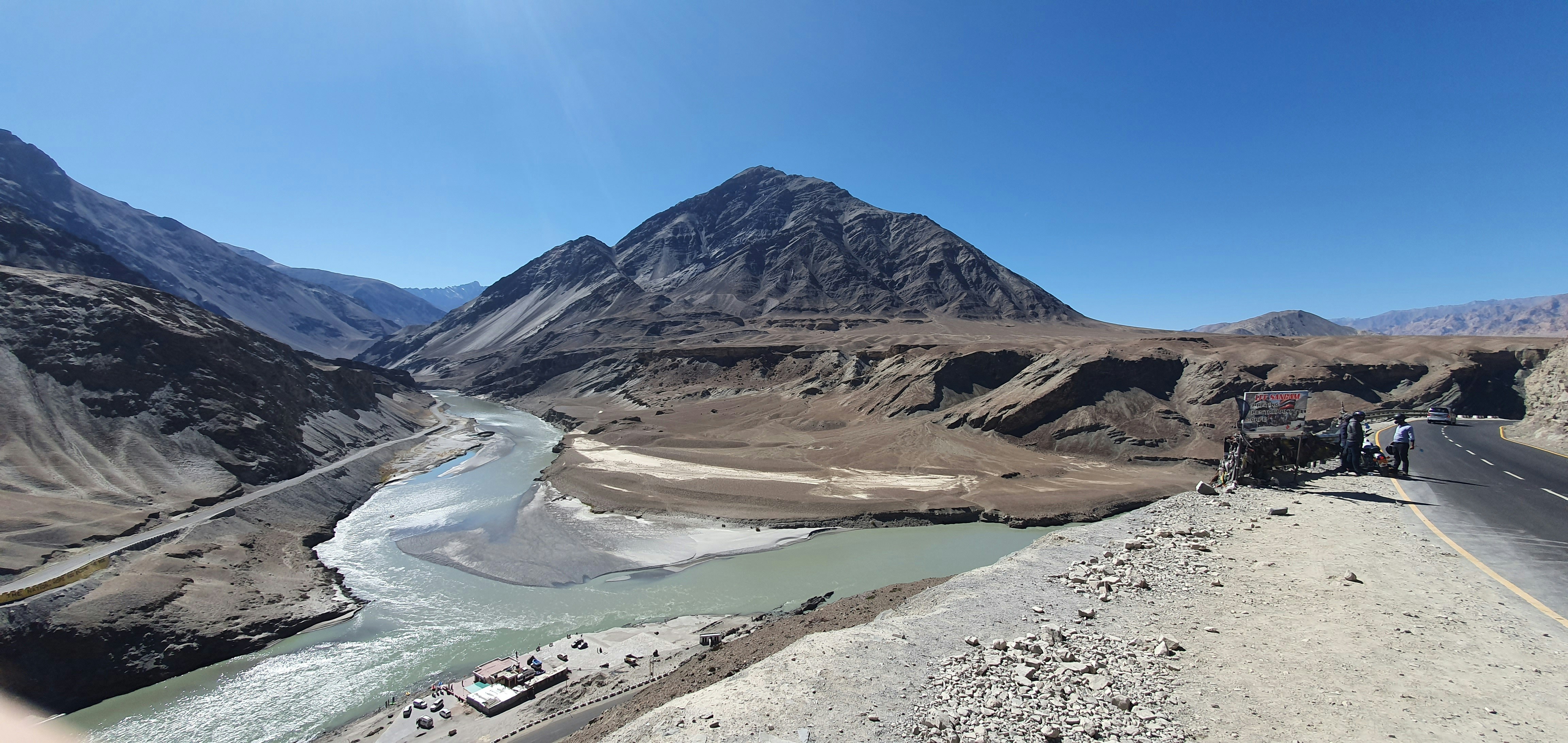 a truck driving down a road next to a mountain range, 