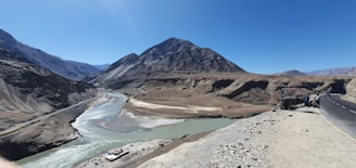 a truck driving down a road next to a mountain range