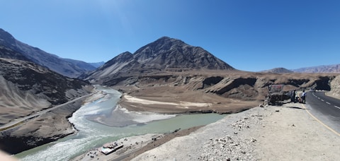 a truck driving down a road next to a mountain range