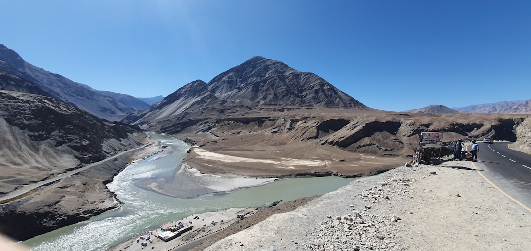 a truck driving down a road next to a mountain range,