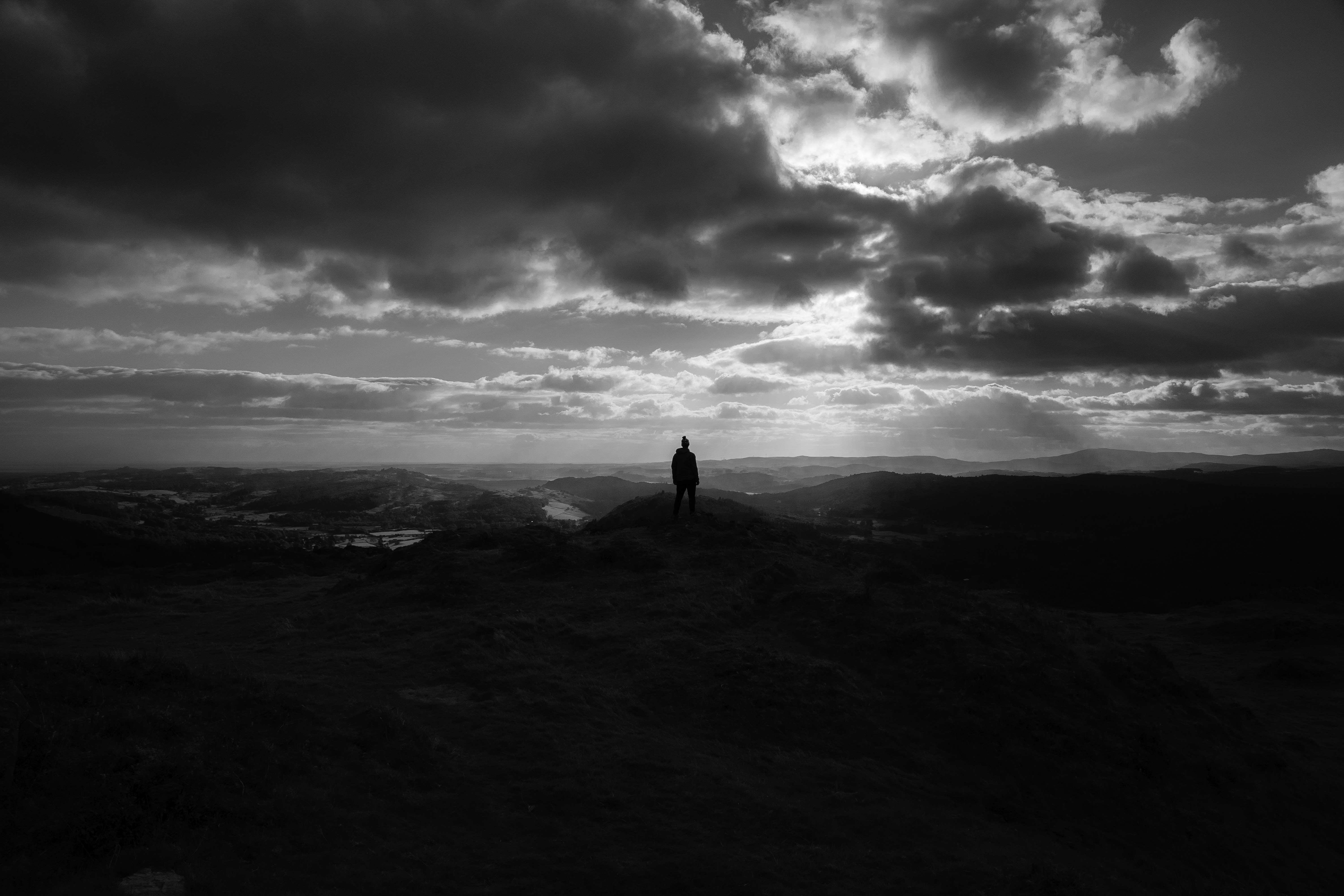 a person standing on top of a hill under a cloudy sky