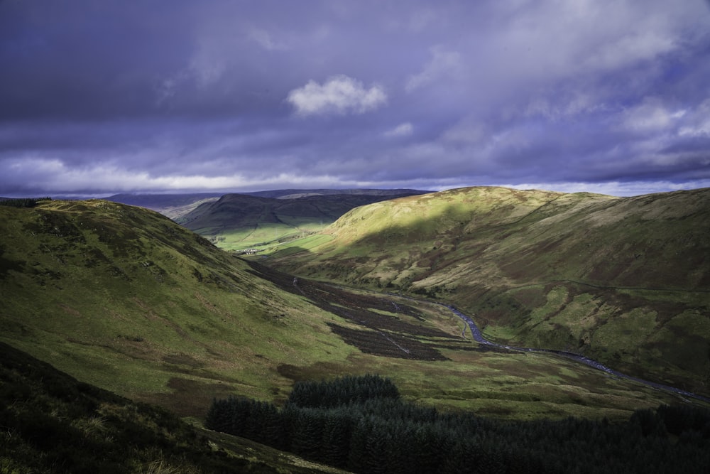 a valley with a river running through it under a cloudy sky