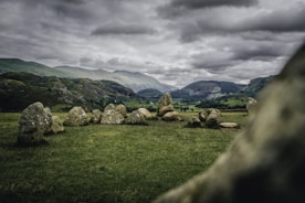 a grassy field with rocks in the foreground and mountains in the background