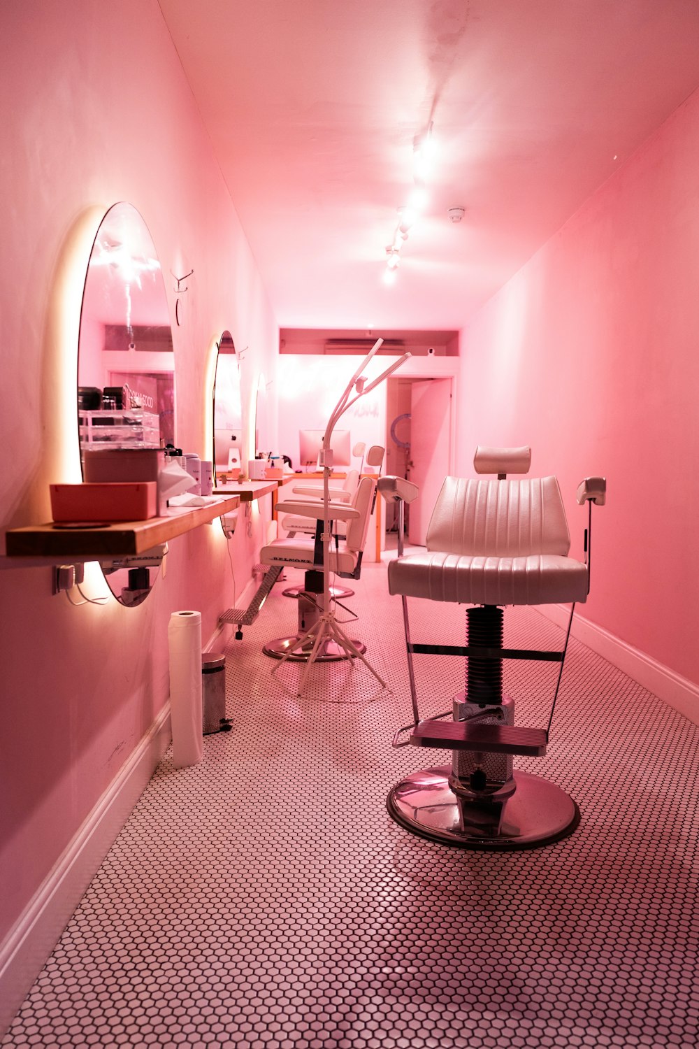 a pink room with a chair and a mirror