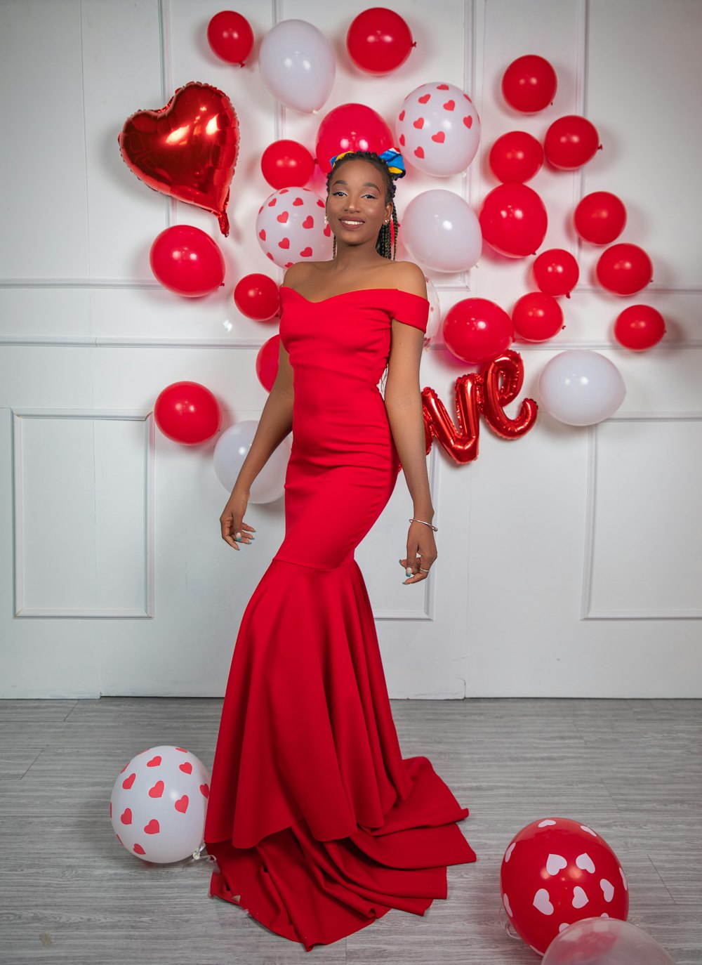 a woman in a red dress standing in front of balloons