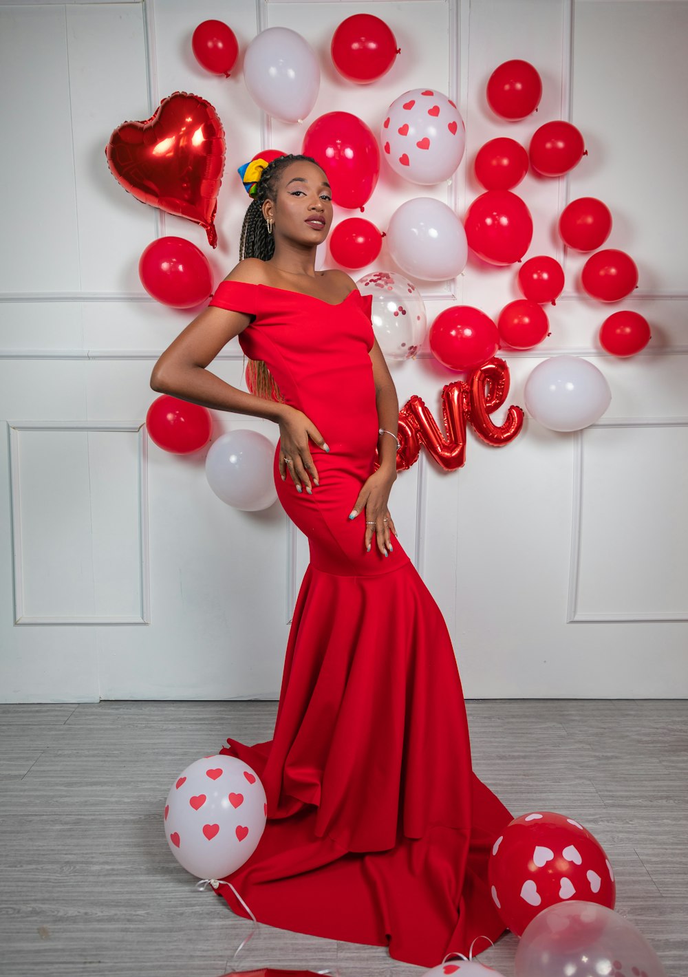 a woman in a red dress standing in front of balloons