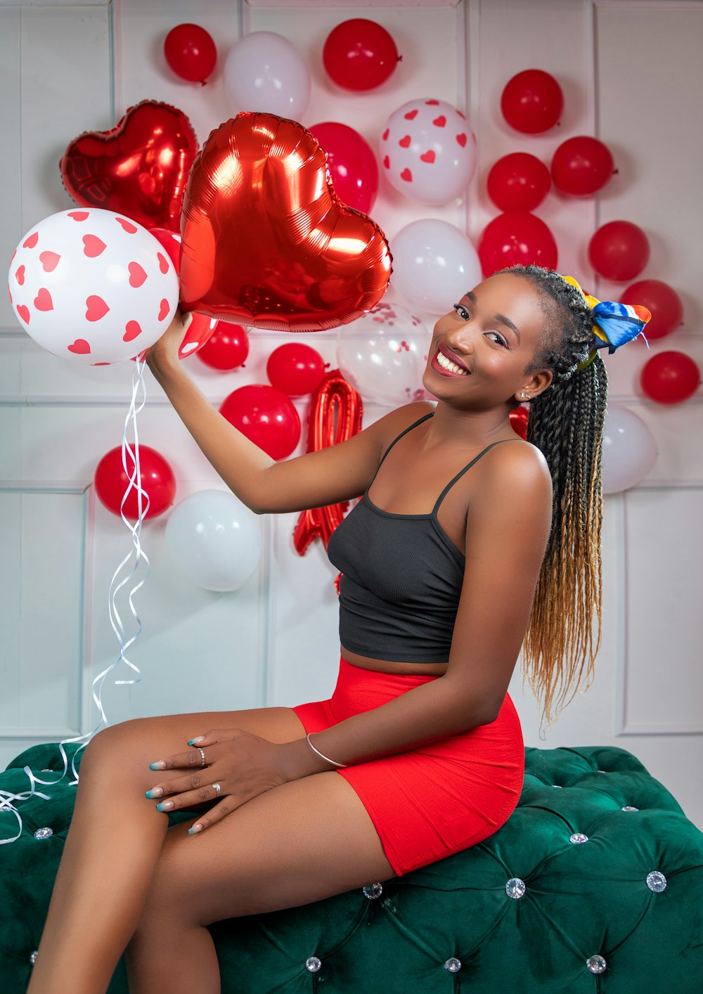 a woman sitting on a bed holding balloons