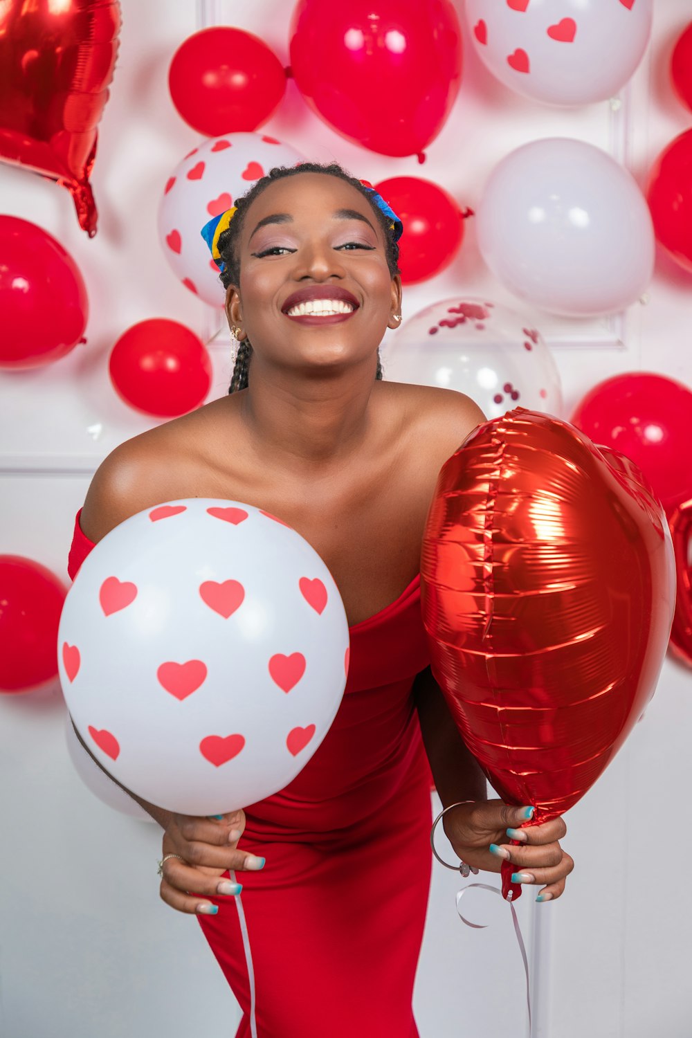 a woman in a red dress holding two red and white balloons