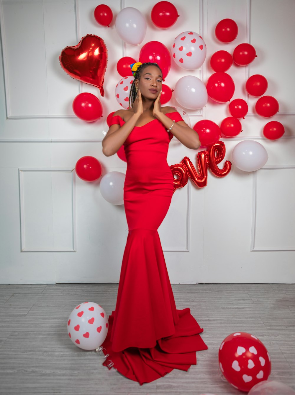 a woman in a red dress standing in front of balloons