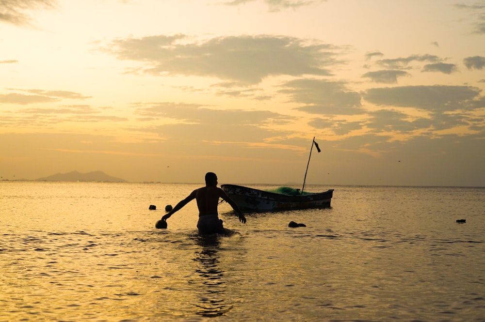 a person standing in the water with a boat in the background