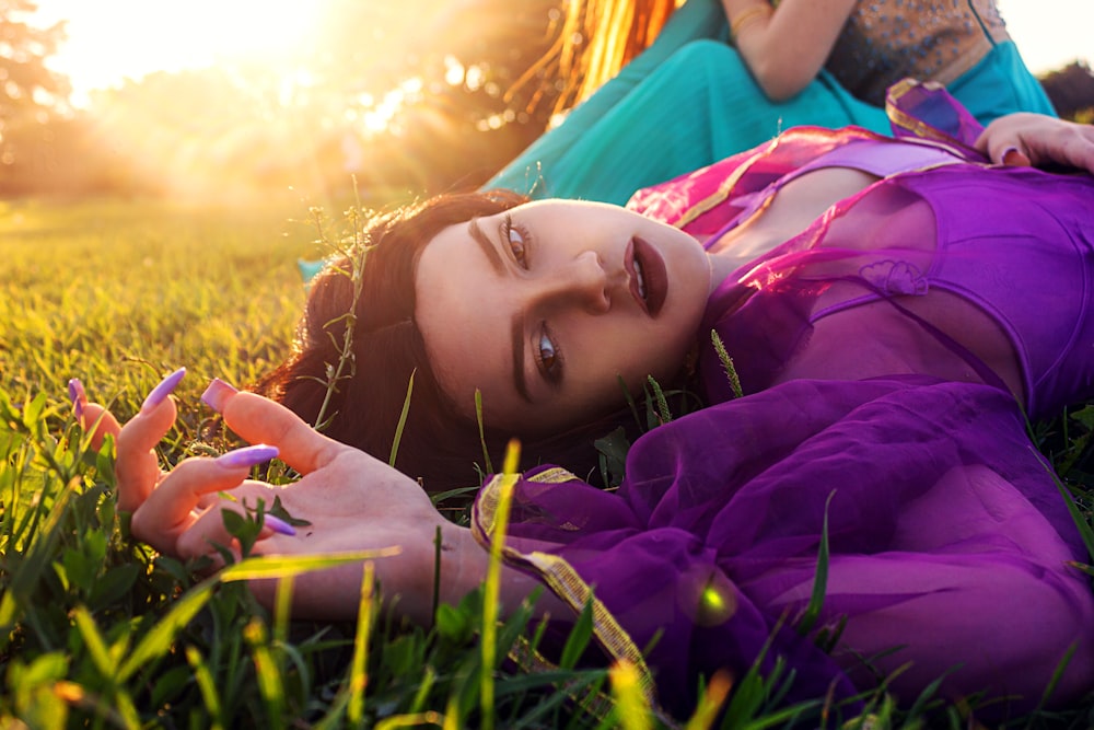 a woman laying on the grass with her hands in her hair