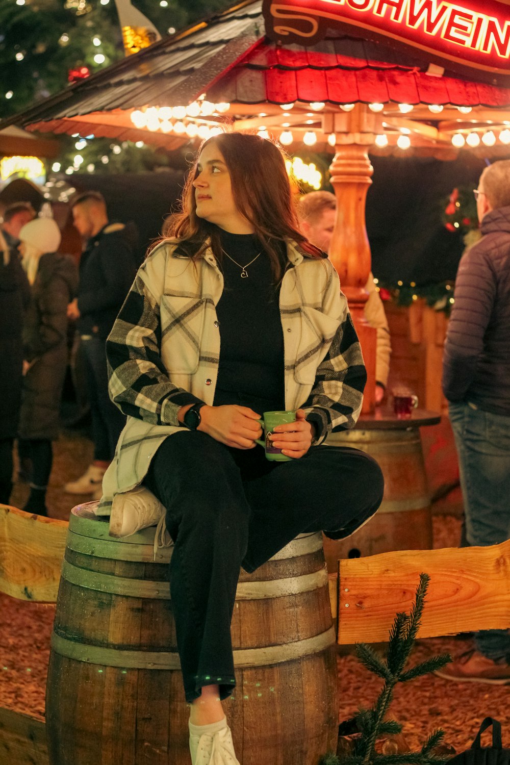 a woman sitting on top of a wooden barrel