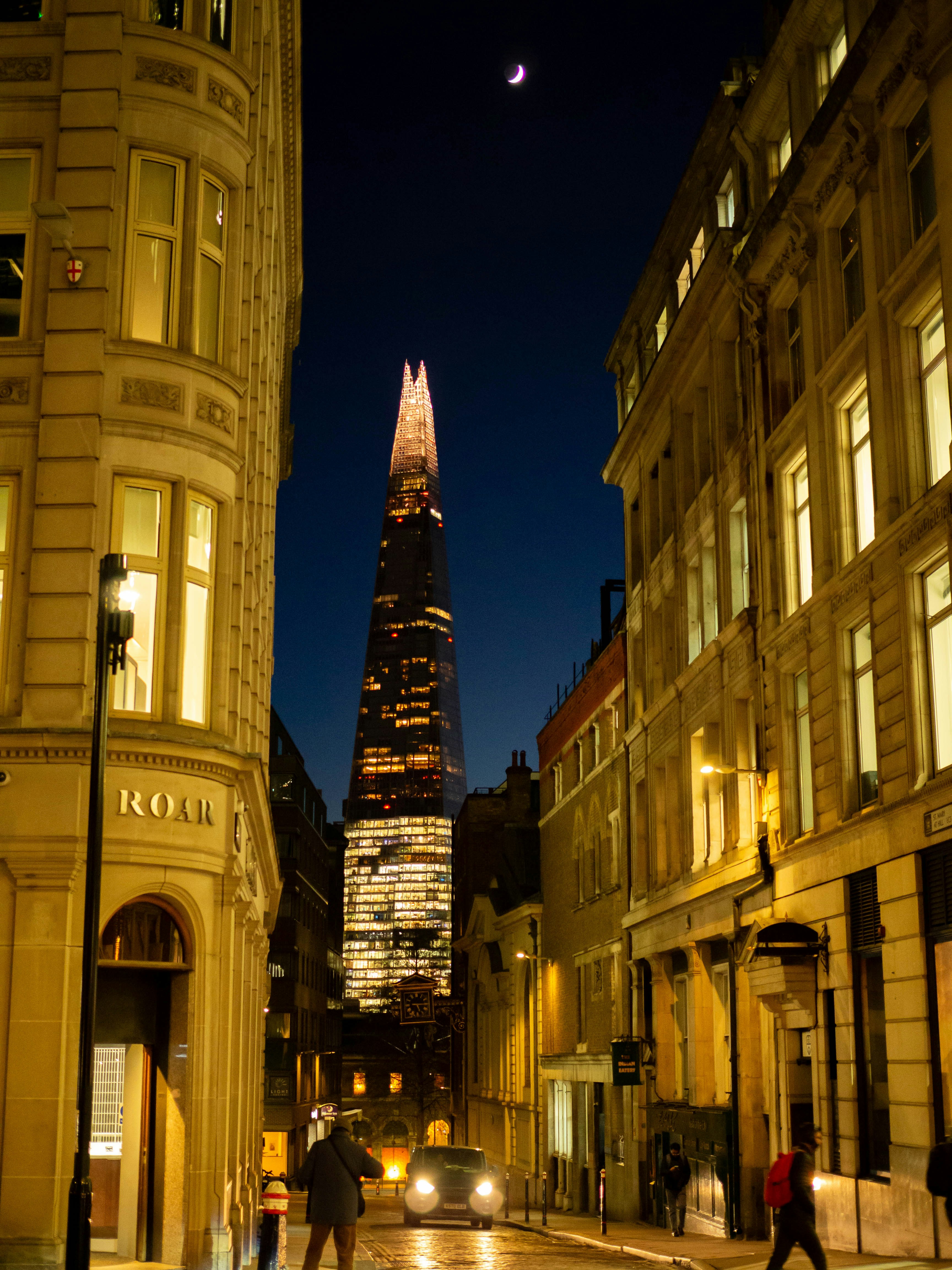 a city street at night with a tall building in the background