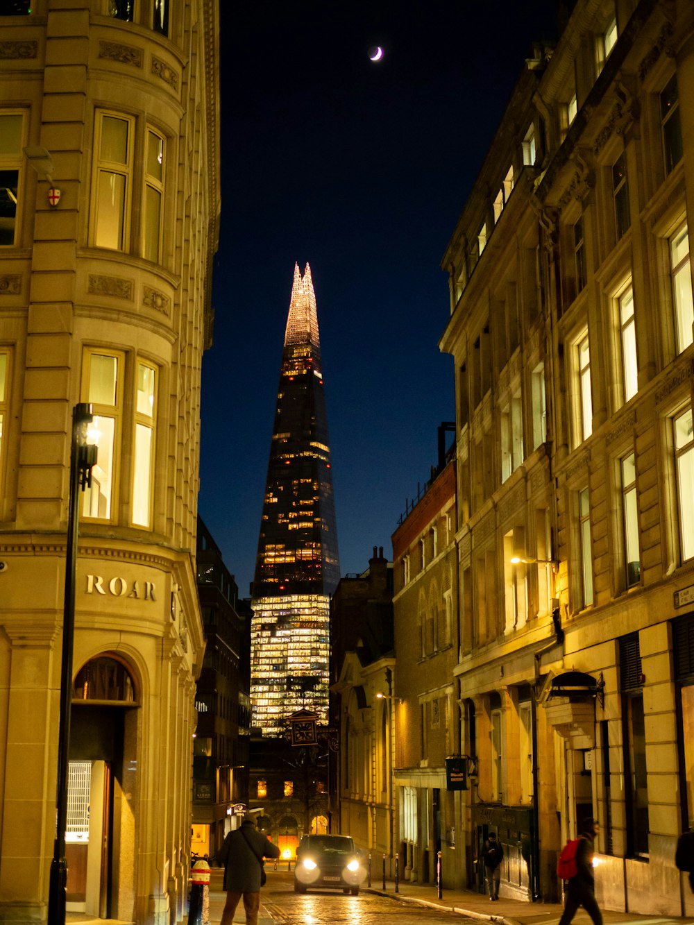 a city street at night with a tall building in the background