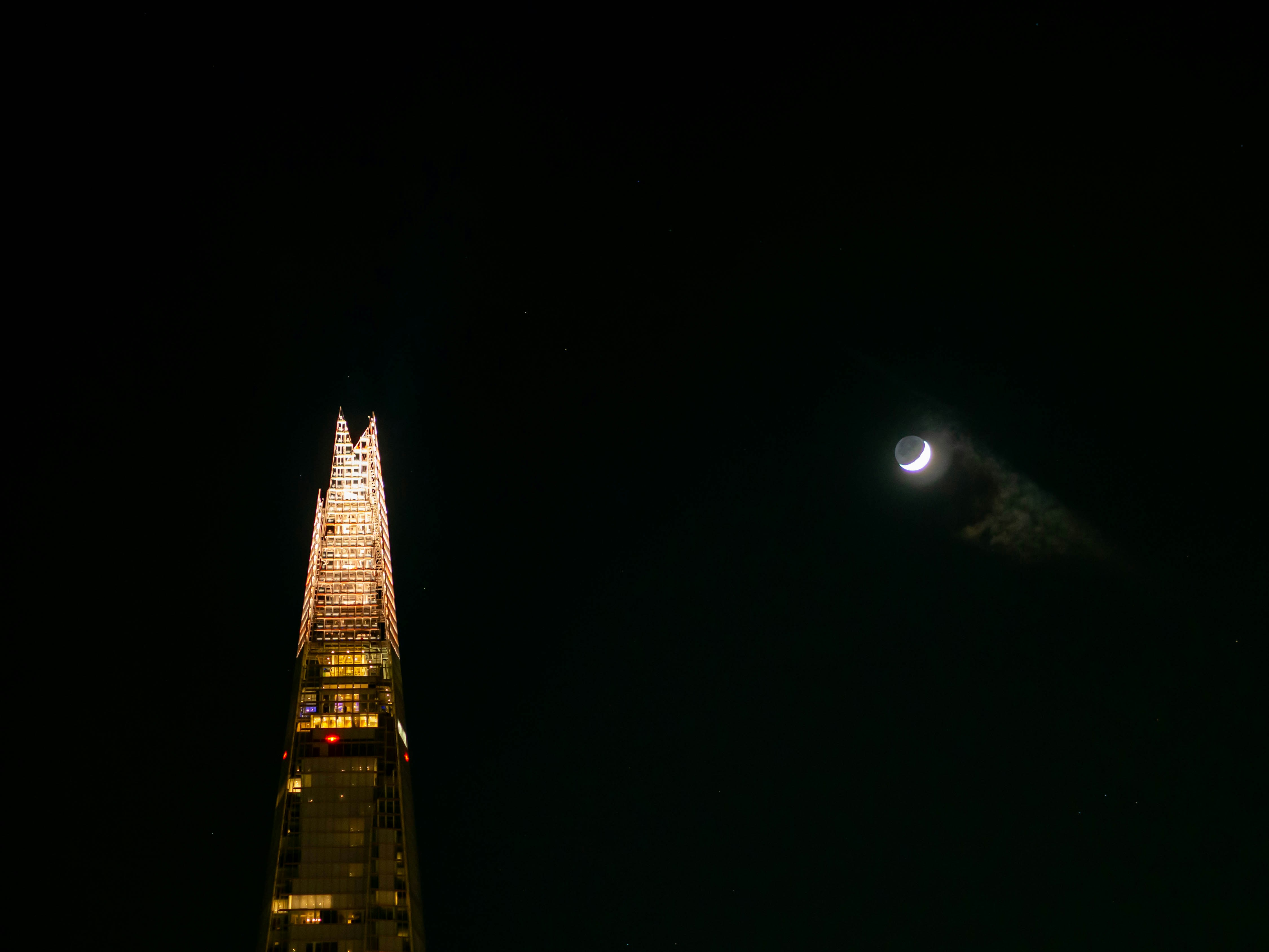 a very tall building with a moon in the sky