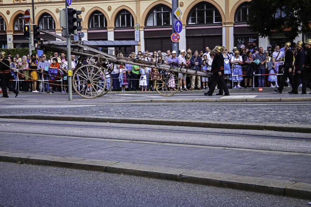 a crowd of people watching a man on a horse drawn carriage