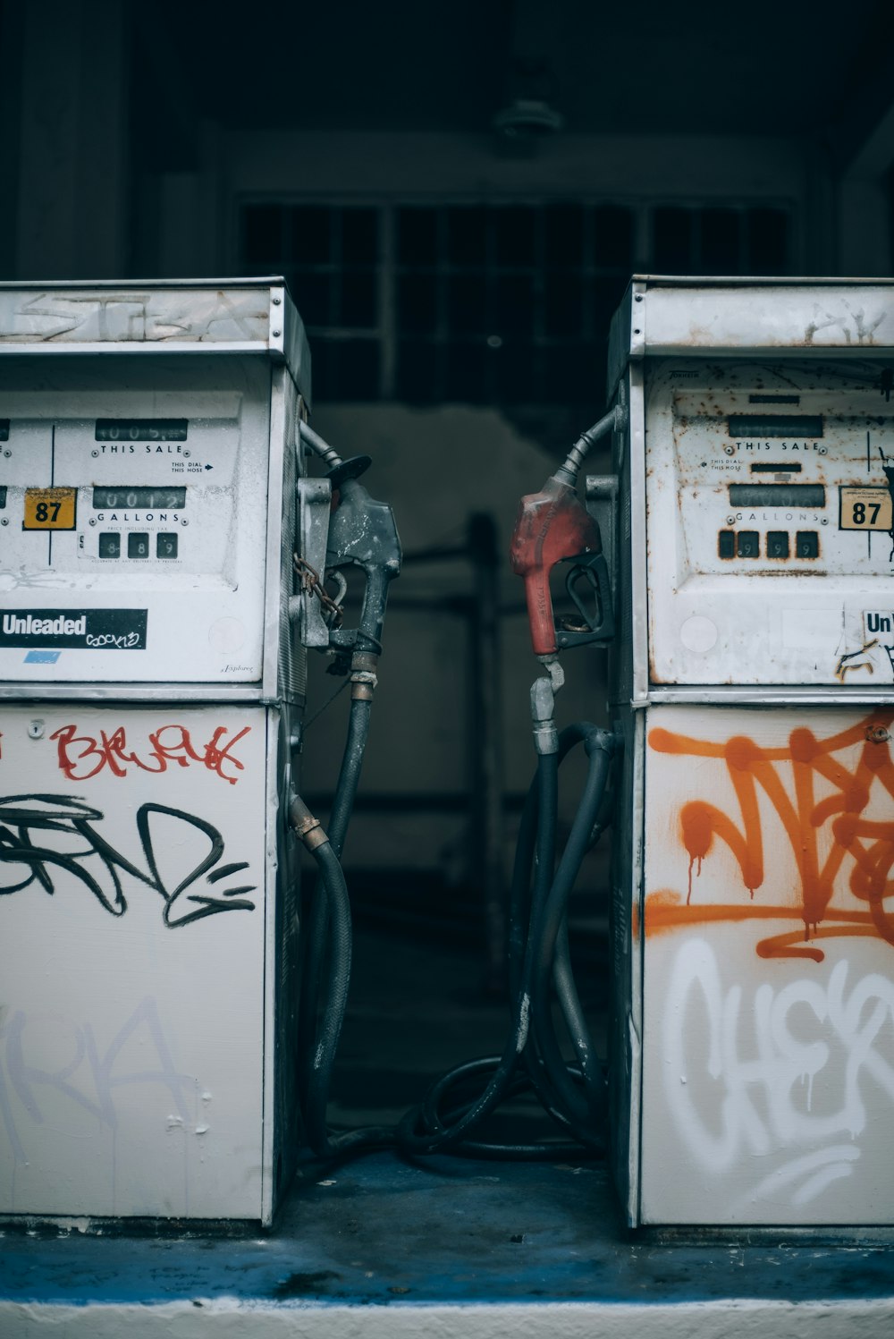 two old gas pumps with graffiti on them