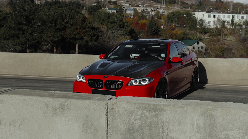 a red and black car parked on the side of a road