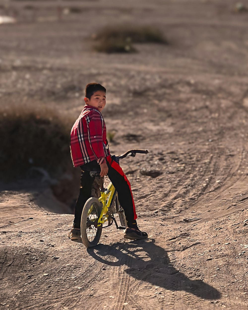 a young boy riding a bike on a dirt road