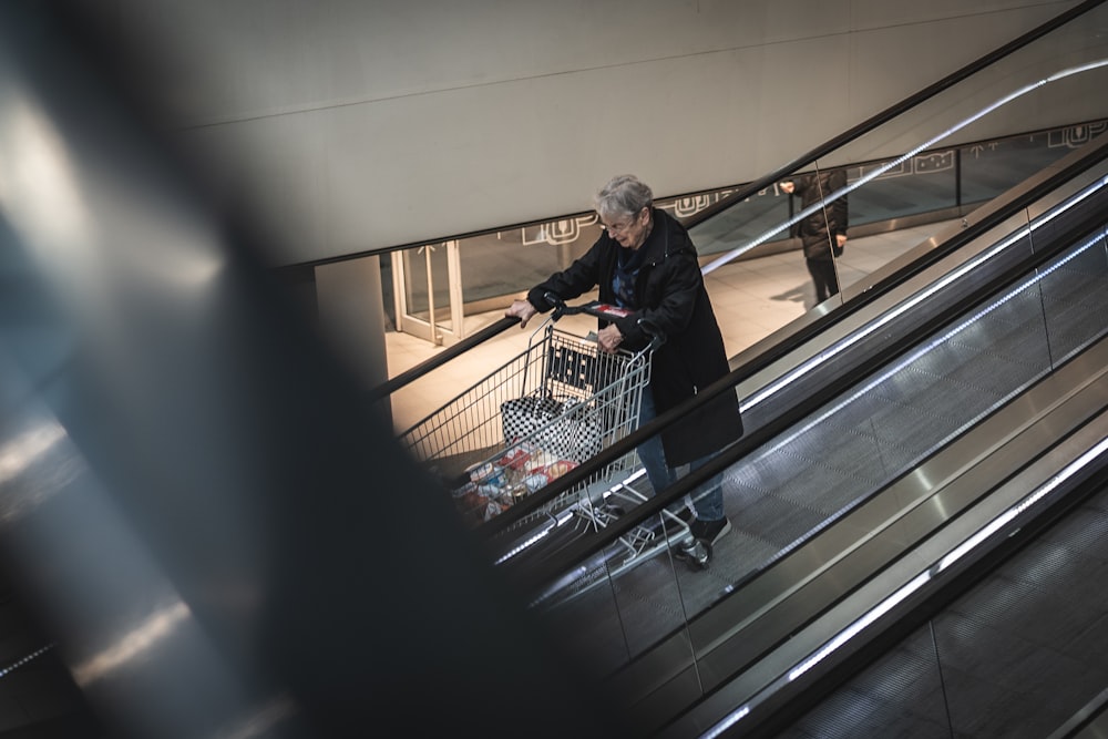 a man pushing a shopping cart down an escalator