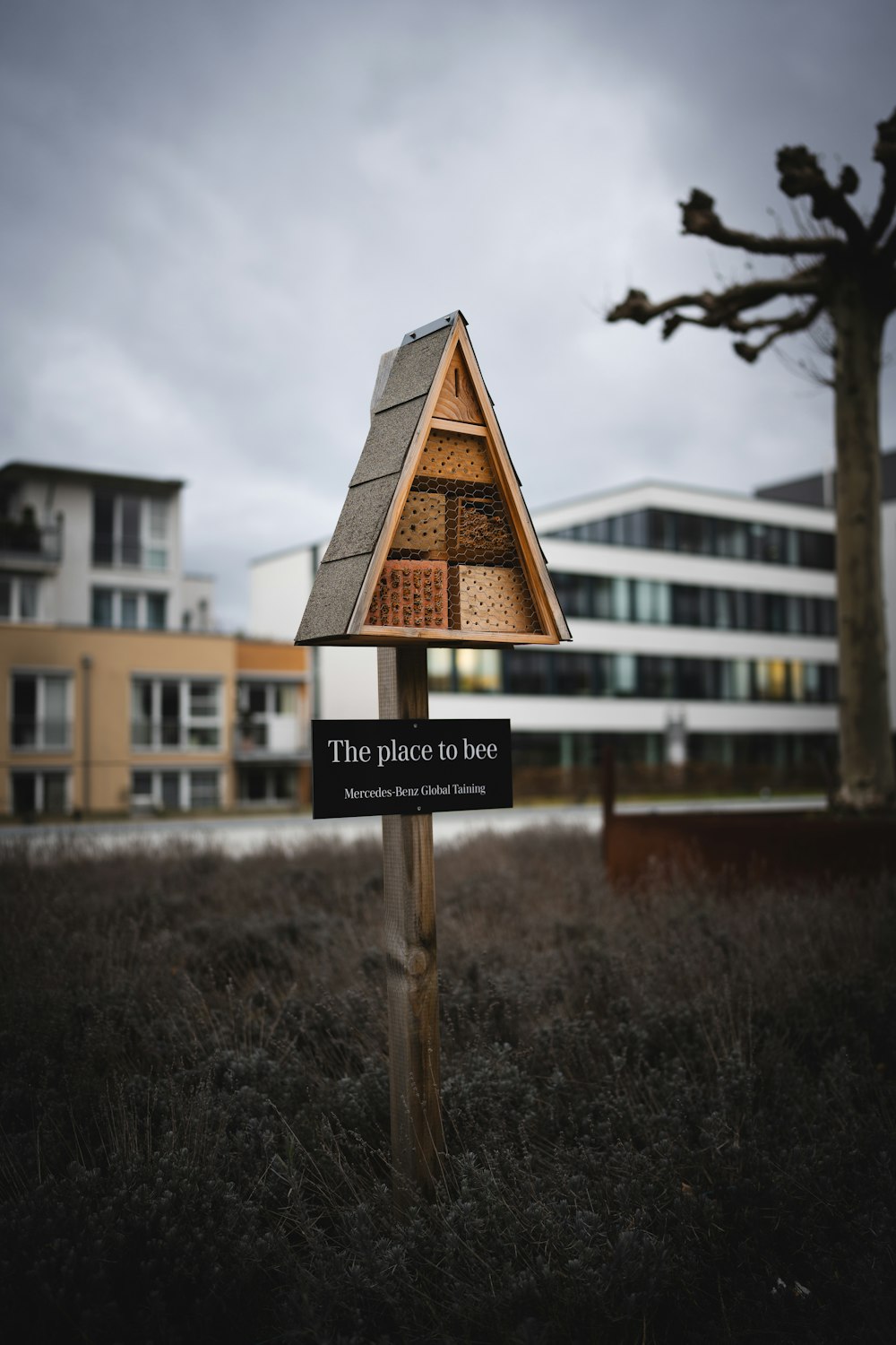 una casita de madera para pájaros con un letrero frente a un edificio