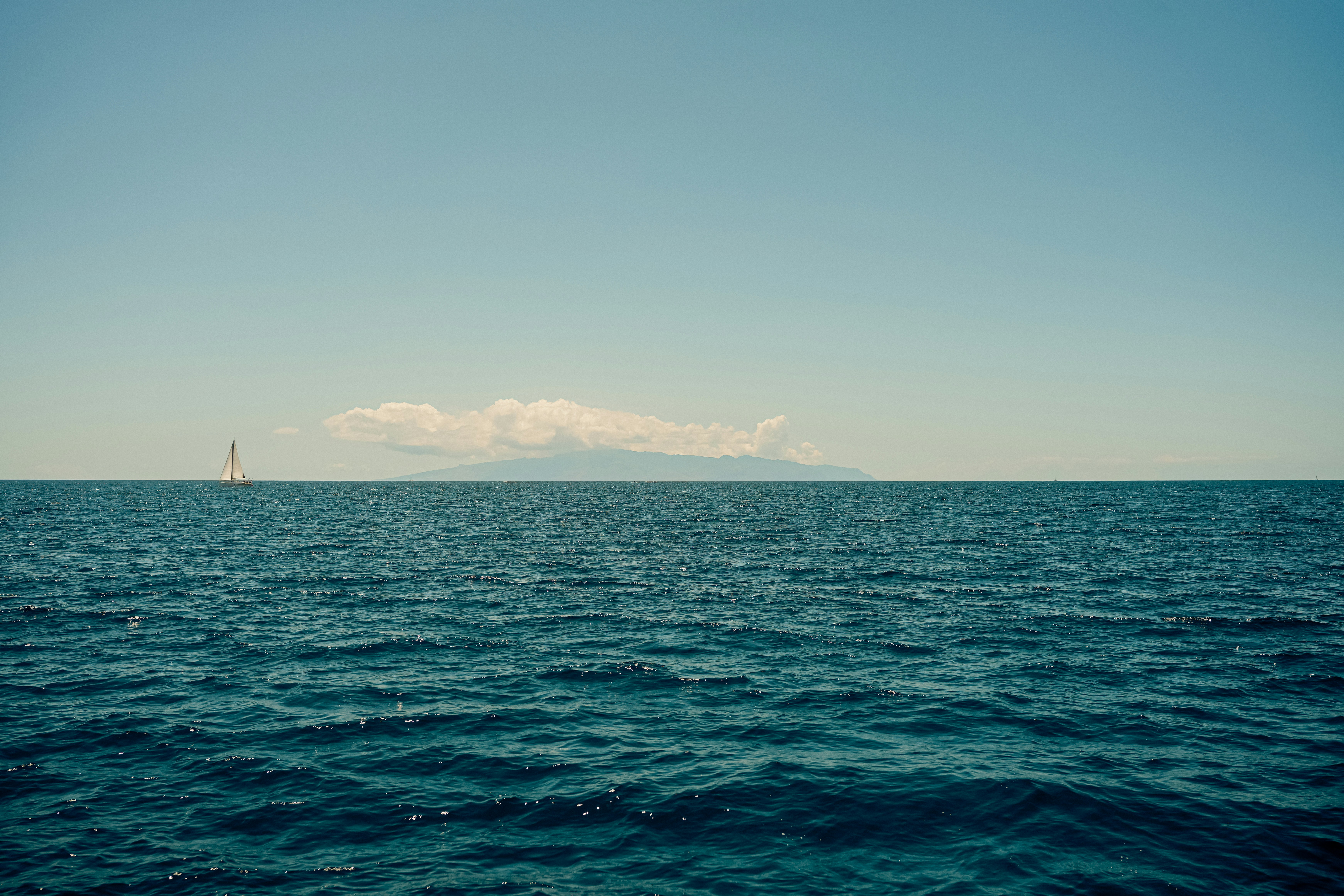 a large body of water with a sailboat in the distance