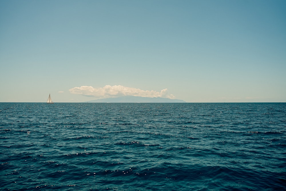 a large body of water with a sailboat in the distance