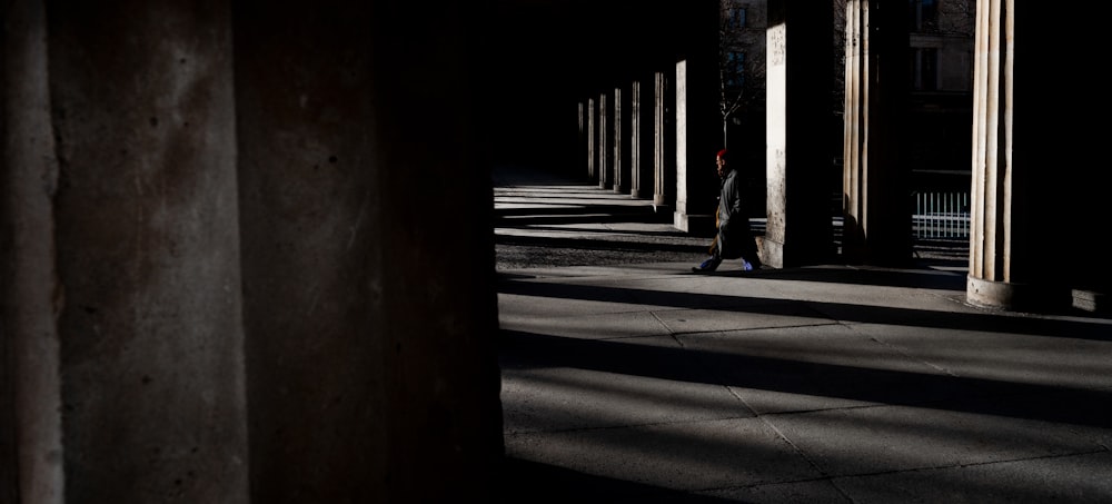 a person walking down a street next to tall pillars