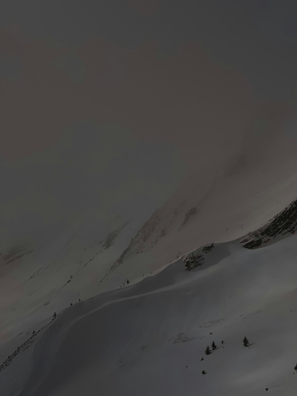 a mountain covered in snow under a cloudy sky