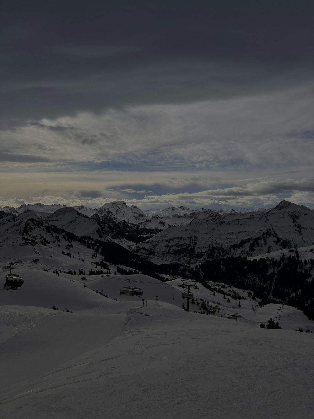 a view of a snowy mountain with a ski lift in the distance