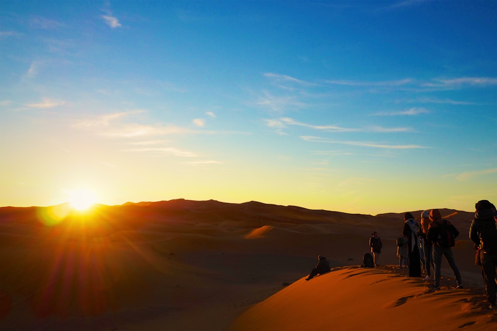 a group of people standing on top of a sand dune