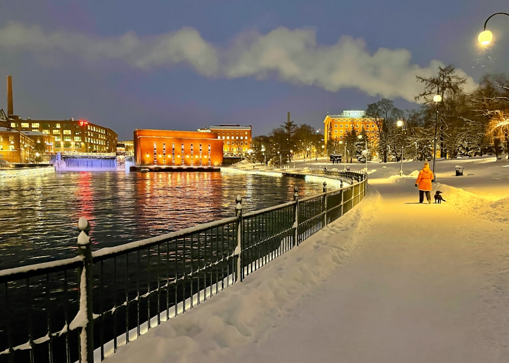 a couple of people walking down a snow covered sidewalk