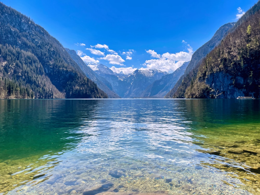 a body of water surrounded by mountains under a blue sky