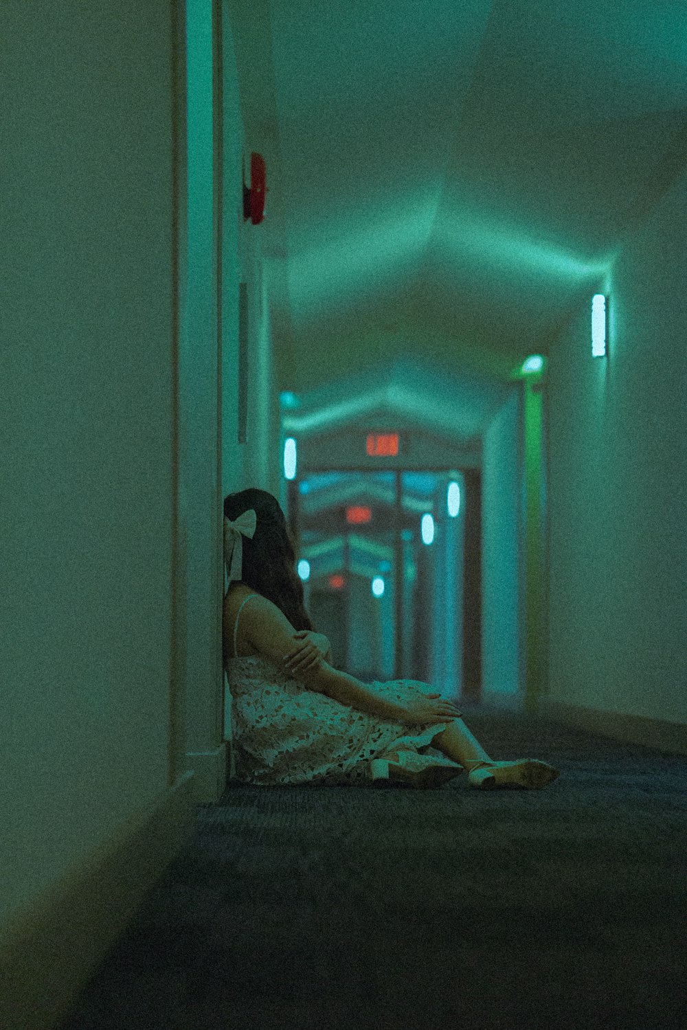 a woman sitting on the floor in a hallway