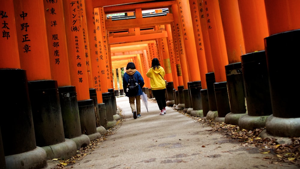 a couple of people walking down a street next to tall buildings