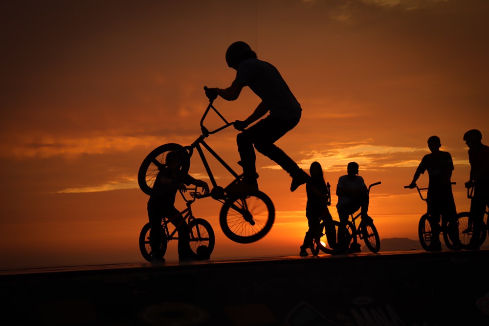 a group of people riding bikes at sunset