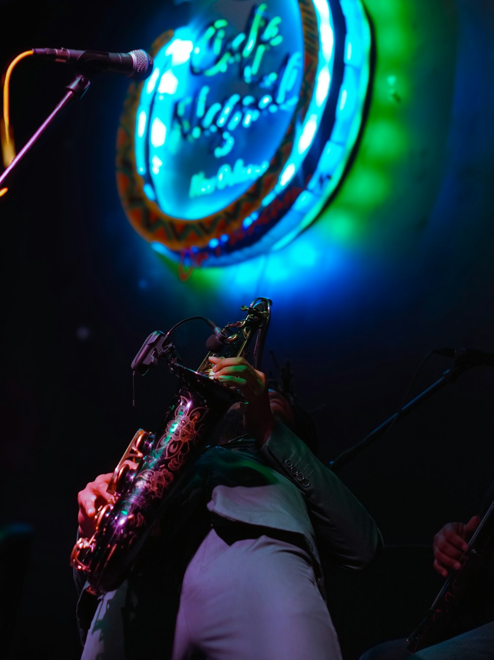 Un hombre tocando un saxofón frente a un letrero de neón