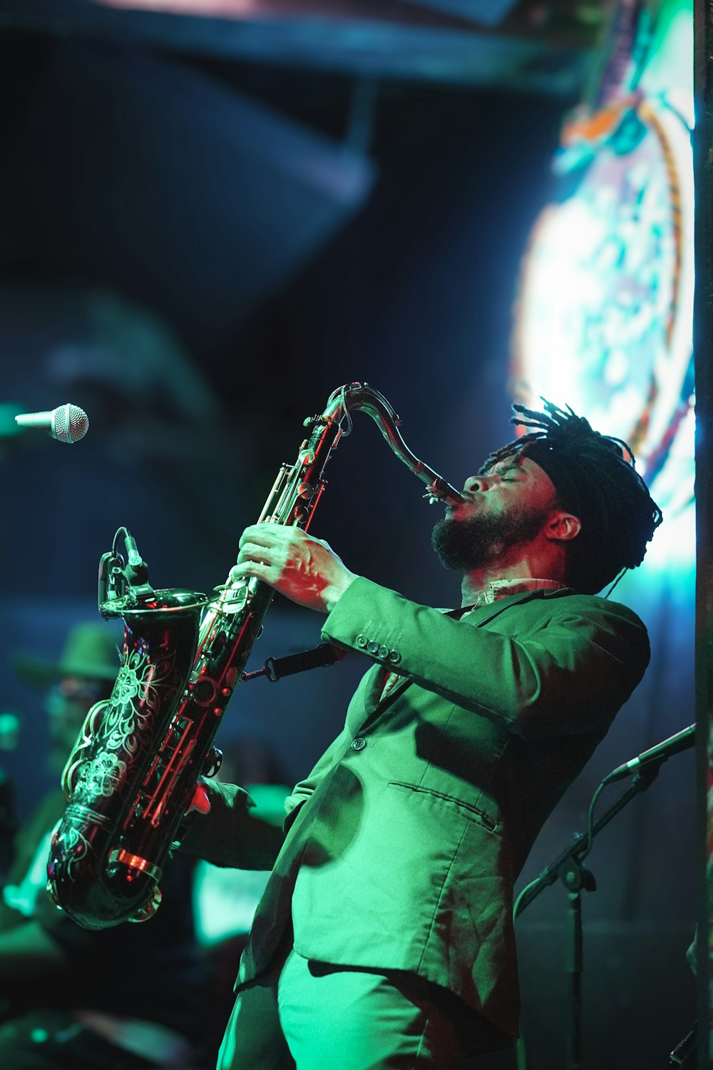 Un hombre con traje verde tocando un saxofón
