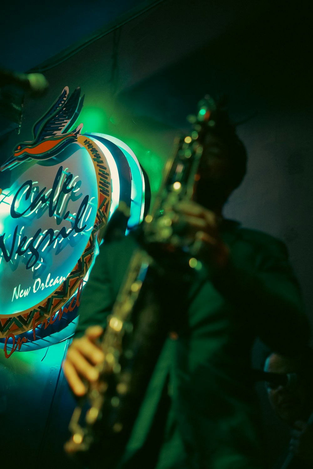 a man playing a saxophone in front of a neon sign