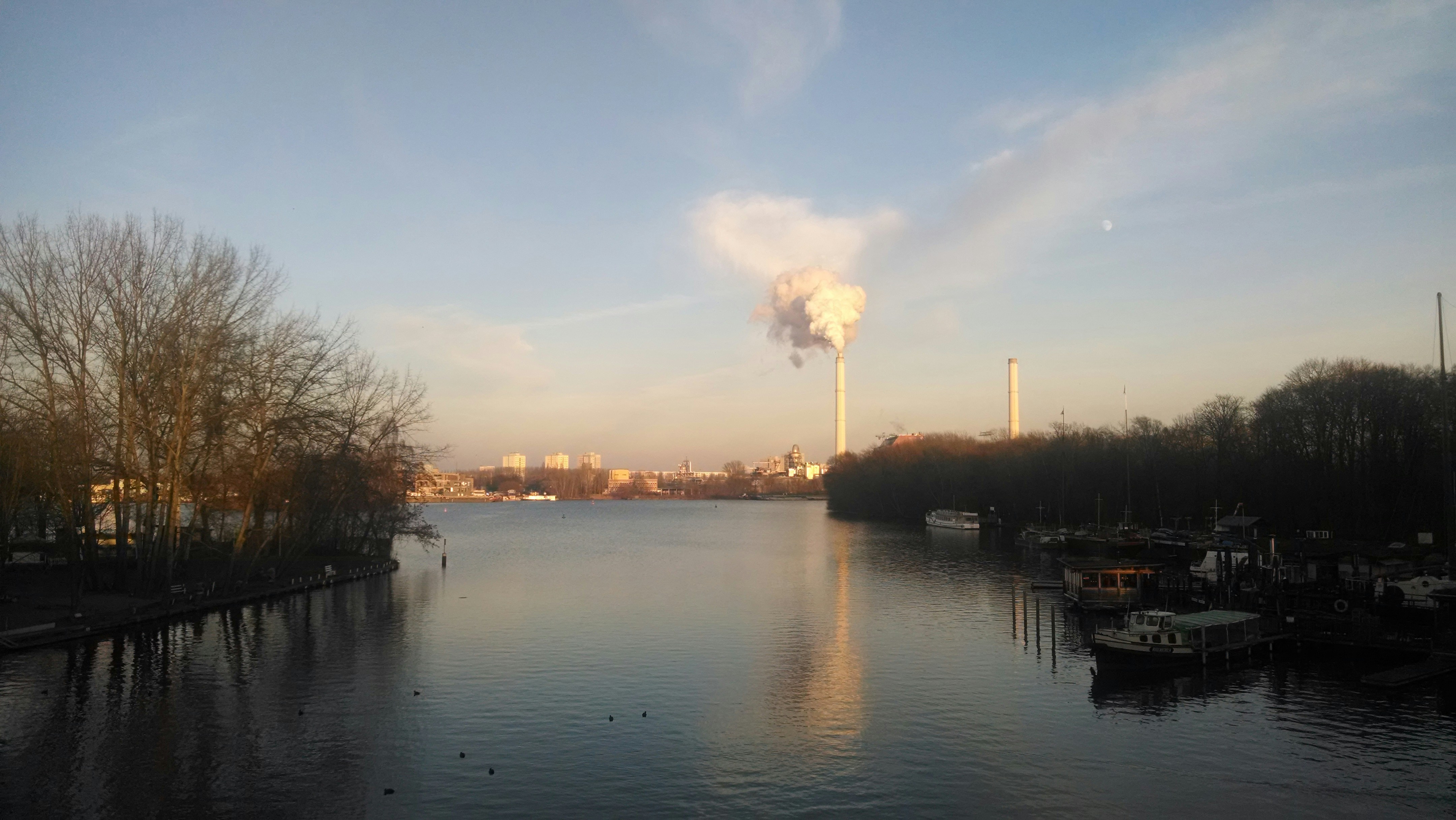a body of water with a factory in the distance