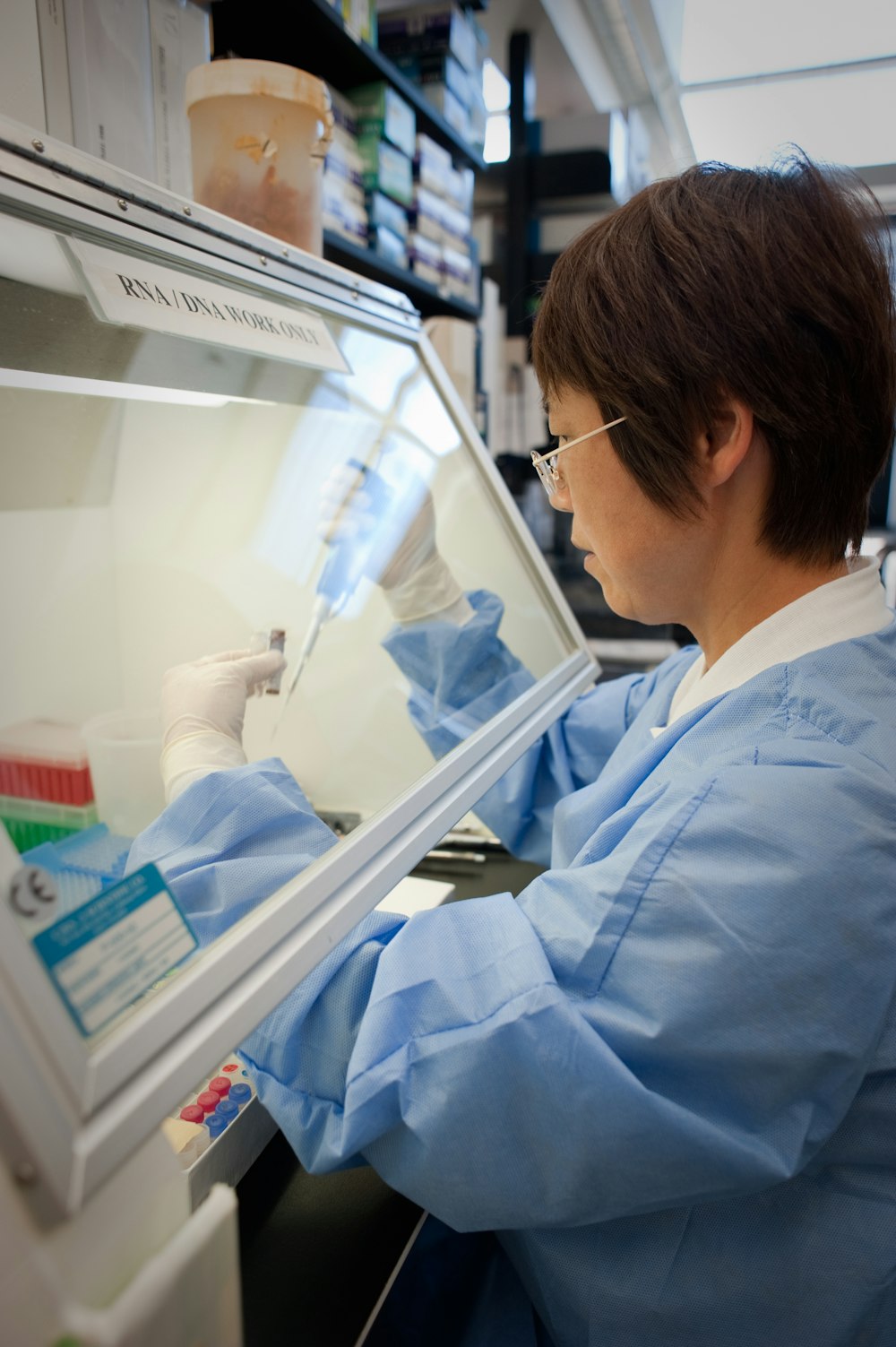 a woman in a lab coat is looking into a freezer