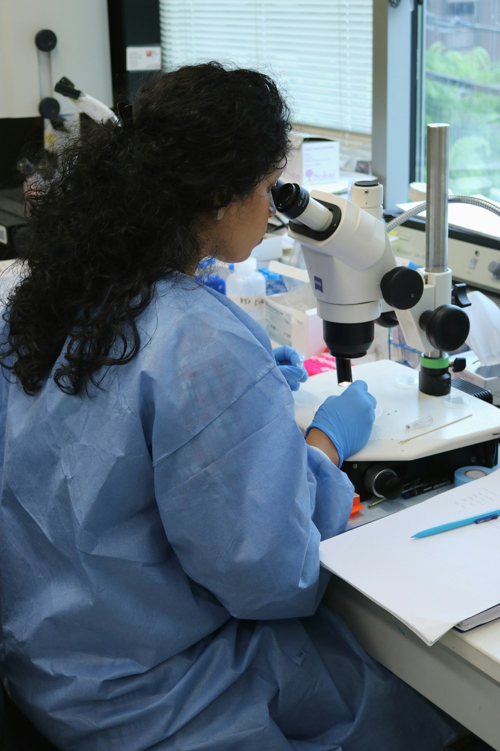 a woman in a lab coat looking through a microscope