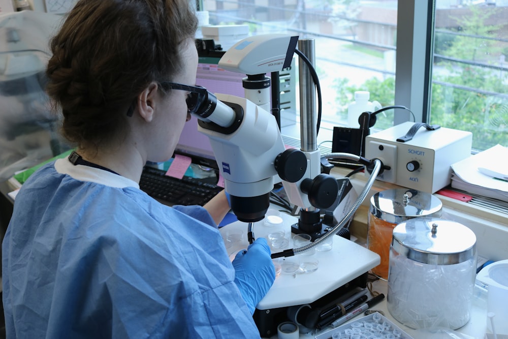 a woman in a lab coat looking through a microscope