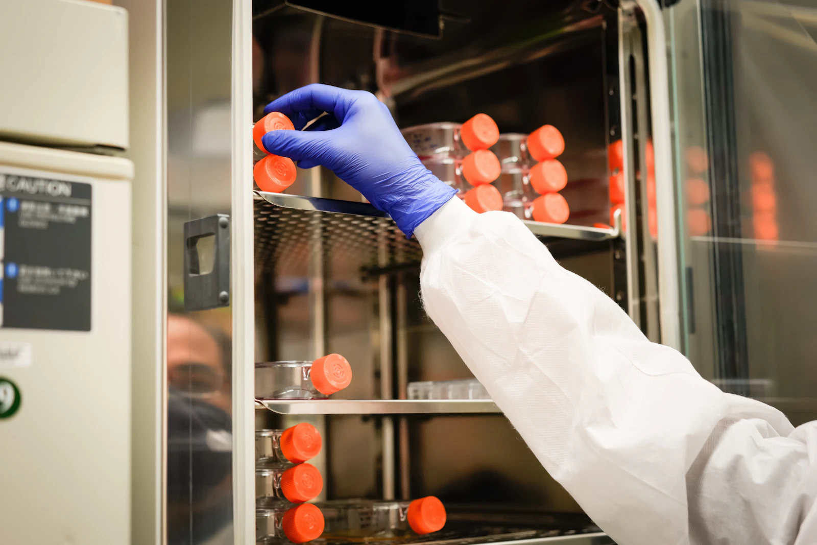 A laboratory technician in a white coat and blue gloves at work