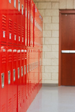 A row of red lockers lining an empty school hallway, representing school climate and discipline policy