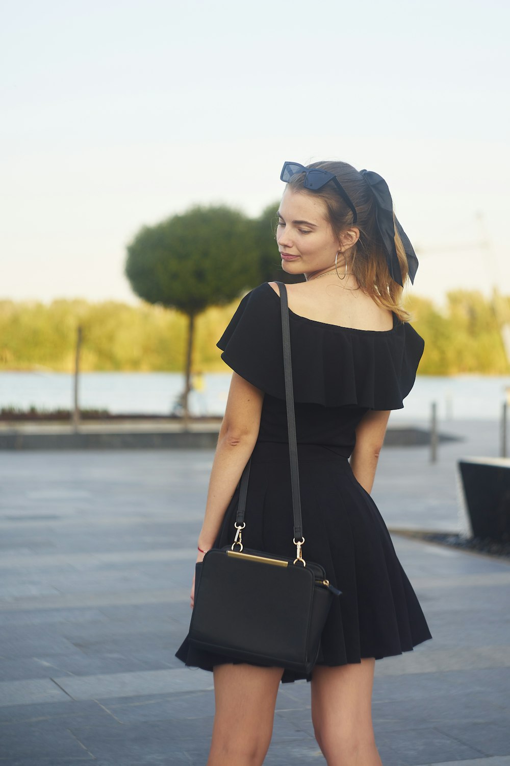 a woman in a black dress is holding a black purse