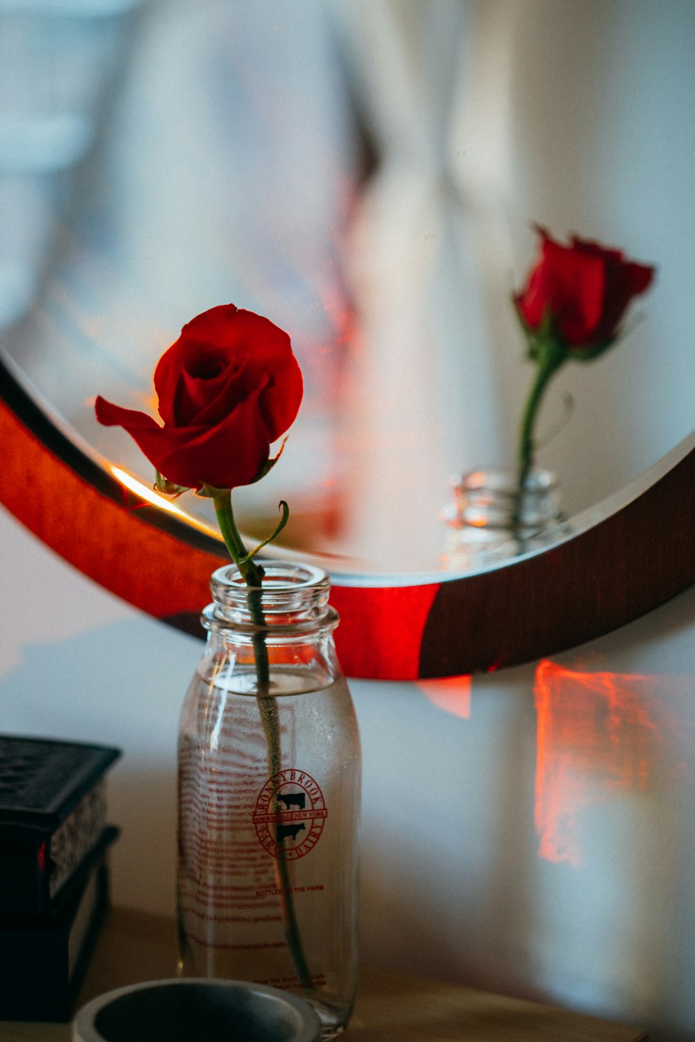 a single red rose sitting in a glass jar