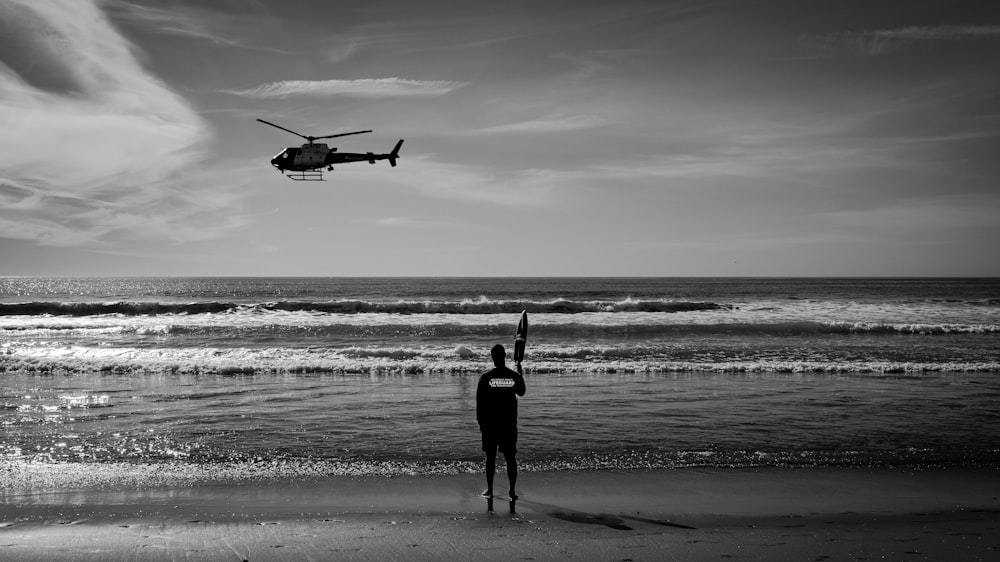 a person on a beach with a helicopter in the sky